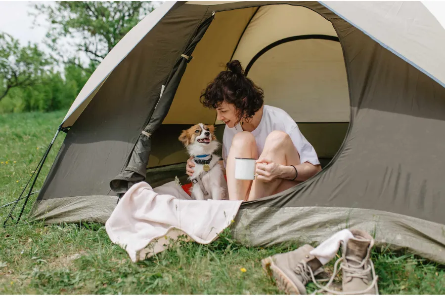 girl and dog sit in camp